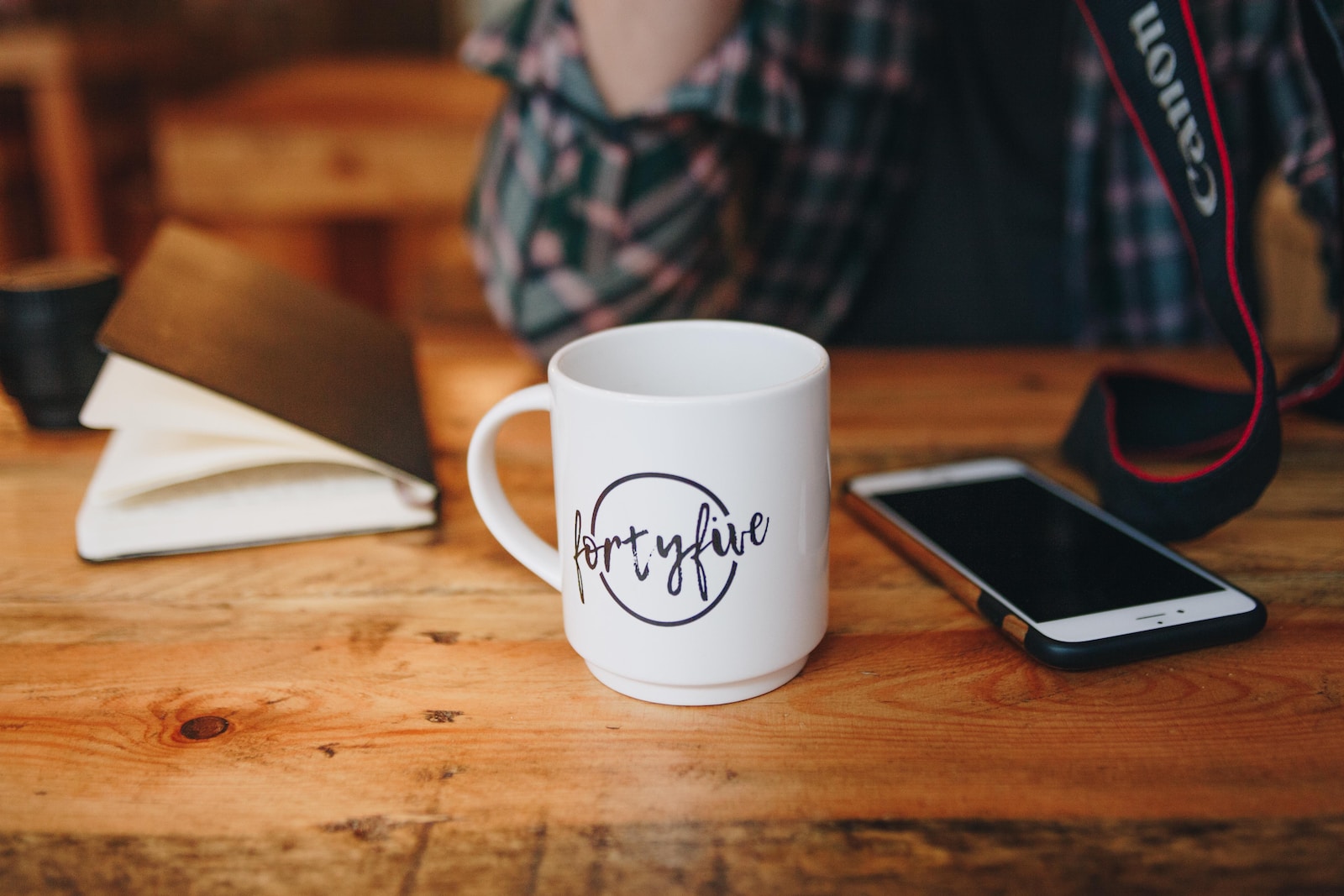 ceramic mug beside a phone on table